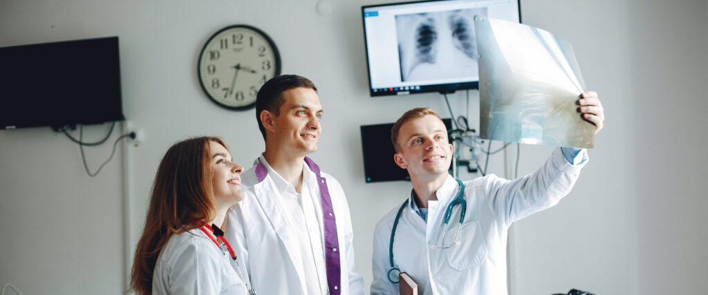 Three interns examine the x-ray in the hospital room.